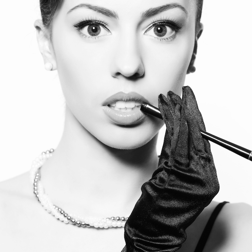 Audrey Hepburn style model wearing a pearl necklace in a black and white photo